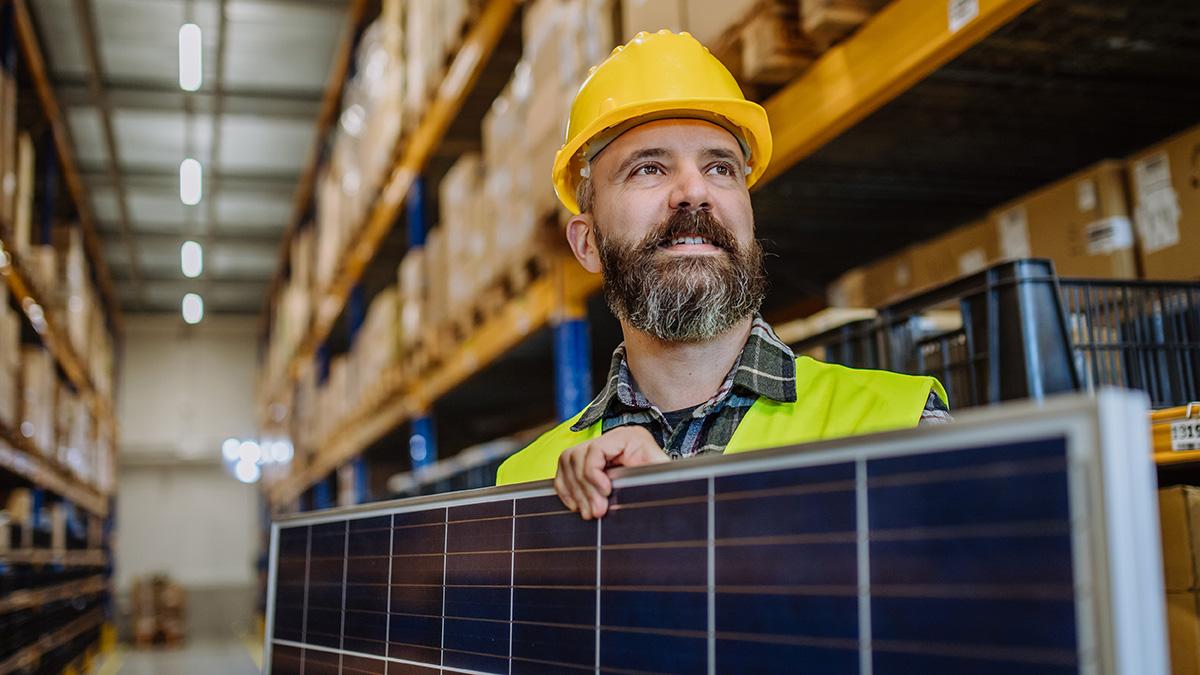 Worker walking through warehouse with solar panels